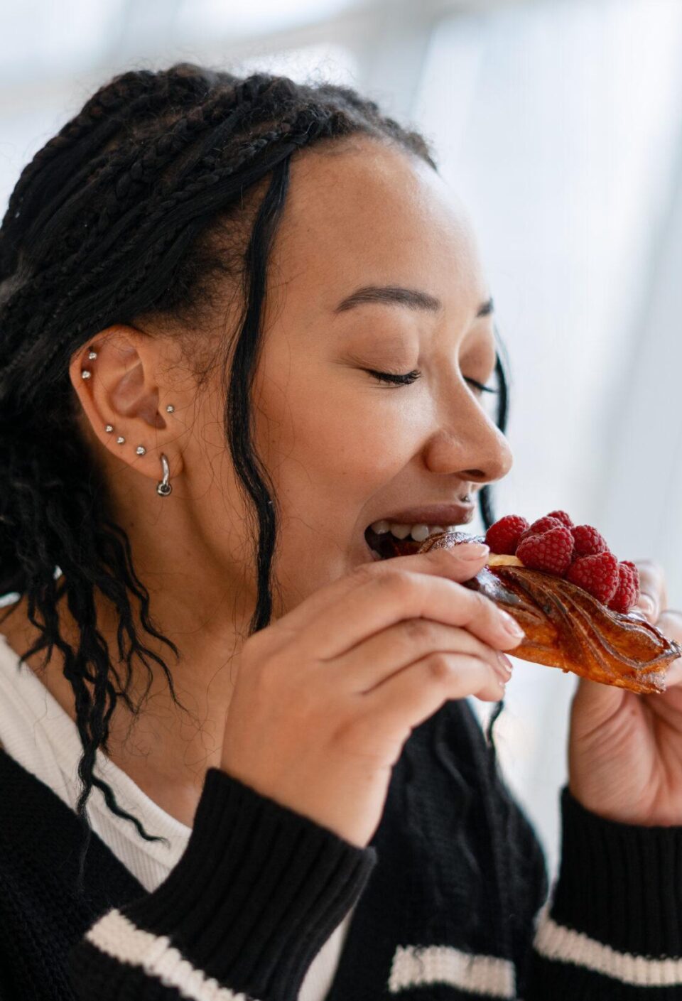 Beautiful African American woman enjoying sweet raspberry pastry in cafe