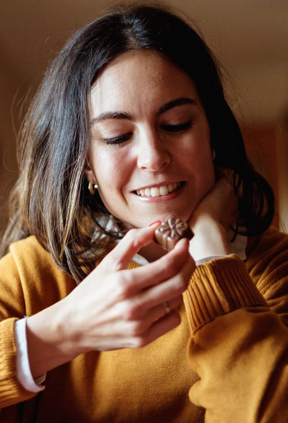 Beautiful young woman eating chocolate in candid kitchen