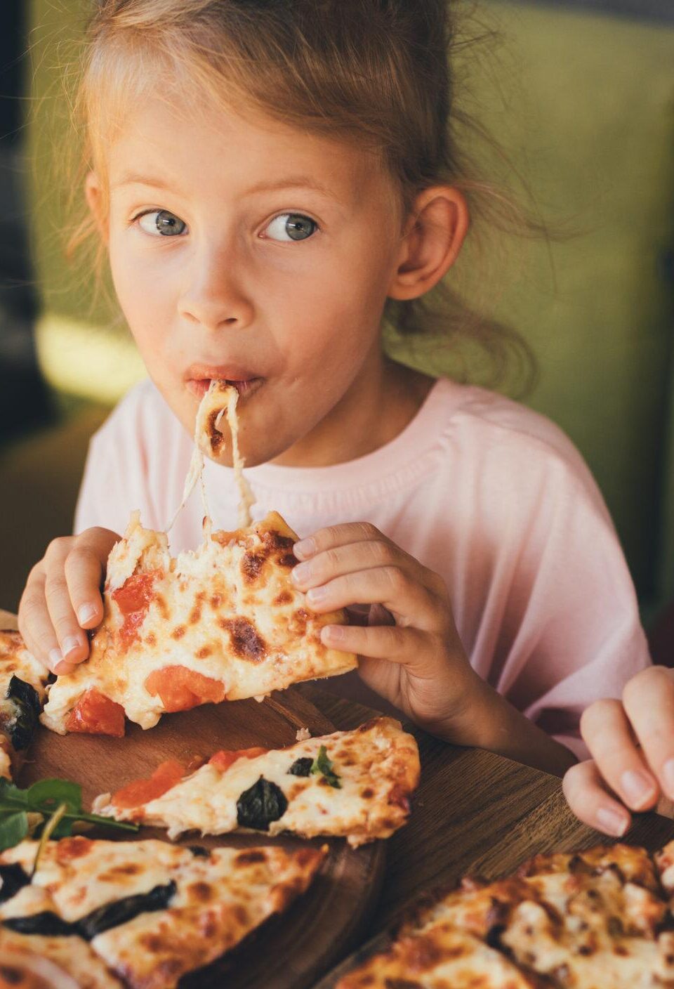 Mother and daughter eat pizza in a cafe.
